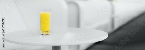 Gray sofa  table  glass of yellow juice. Minimalistic style outdoor interior. Demonstrating trendy Color of the Year 2021. Illuminating Yellow  Ultimate Gray. Duotone. Depression treatment. Banner