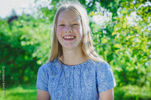 portrait of a  smiled girl with long  blond hair  of twelve years old outdoor