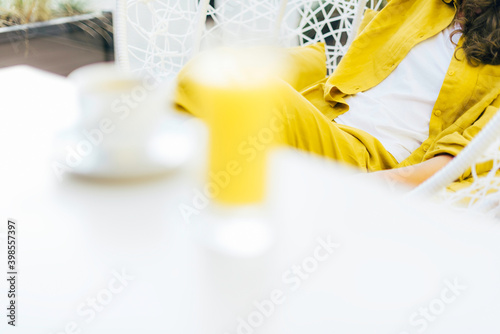 Trendy Illuminating and Ultimate gray duotone picture. Style girl with yellow clothes, glass of juice. Minimalistic style outdoor interior. Demonstrating trendy Color of the Year 2021