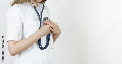Medicine and health concept. Doctor woman listens with a stethoscope to her heart.