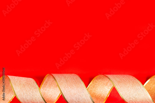 Golden ribbon against red background. gold packaging ribbon curls on red background, new year background, copy space, place for text, banner, holiday concept, Christmas, new year, Valentine's day