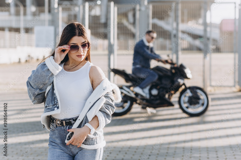 Sexy girl posing on the background of a sports motorcycle, and a guy in denim clothes