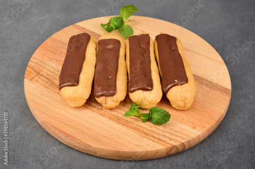 Photos Four eclairs lie on a wooden cutting board