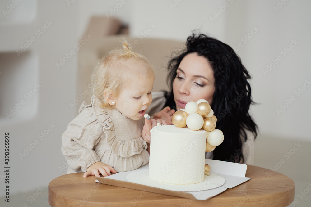 dessert for the holiday. they celebrate their birthday in a large apartment. beautiful girls young mother and little daughter of European appearance, play at home and eat a healthy holiday cake dessert for the holiday. they celebrate their birthday in a large apartment. beautiful girls young mother and little daughter of European appearance, play at home and eat a healthy holiday cake