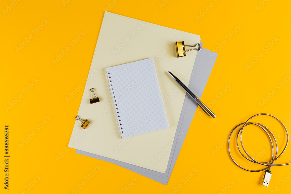 Yellow office desk table with blank notebook and other office supplies. Top view with copyspace, flat lay.