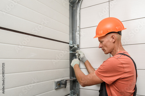 The worker is installing lift gates in the garage.