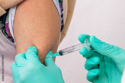 hands of doctor or nurse putting vaccine on arm