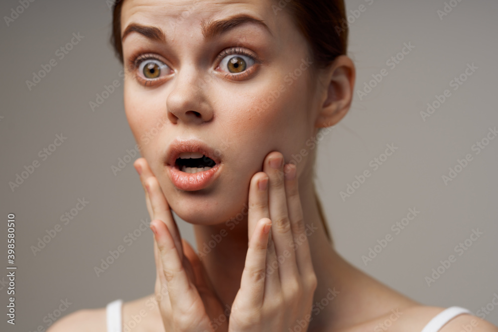 red-haired woman touching face with hands on gray background cropped view red-haired woman touching face with hands on gray background cropped view
