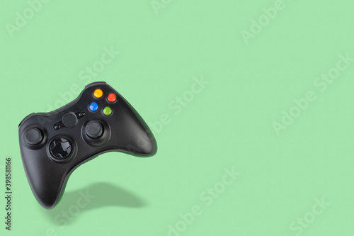 Floating videogame controller over green background with copy space