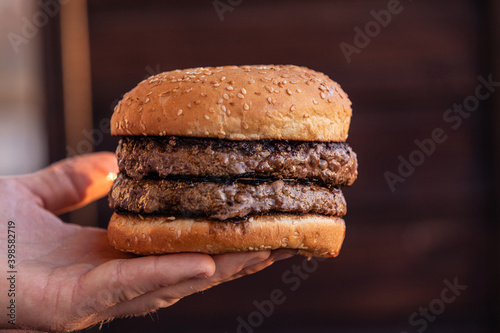 Cropped view of person holding tasty cheeseburger.