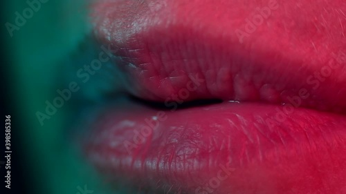 Close up of lips blowing. Colourful lighting macro shot. High quality audio. 