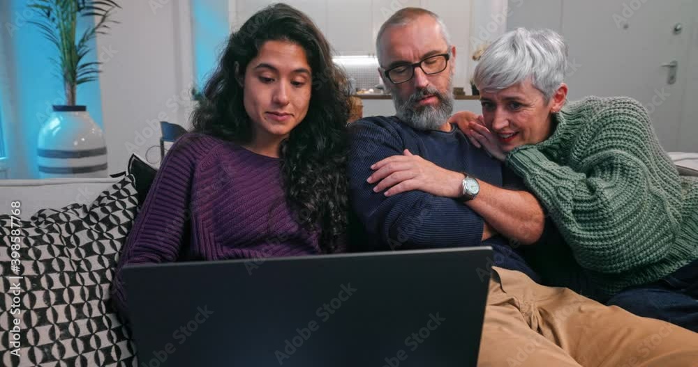 Daughter showing senior parents how to use laptop on sofa