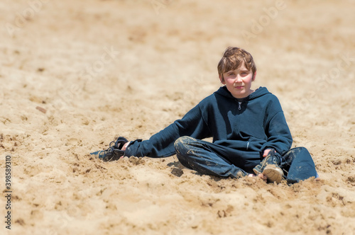 Boy sitting in sand looking at camera