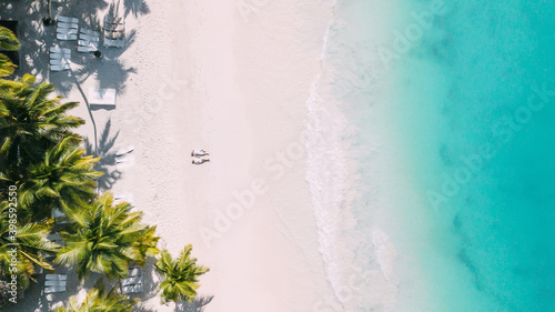 A couple lies and relax on the beach on island. Aerial shoot by drone