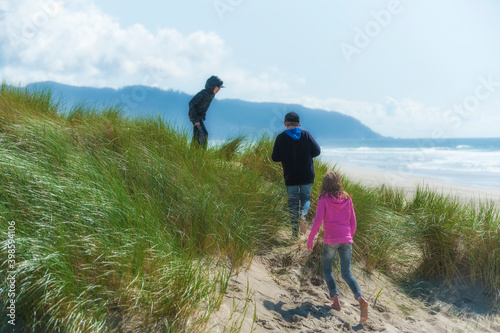 Two boys and a girl explore sand dunes on beach