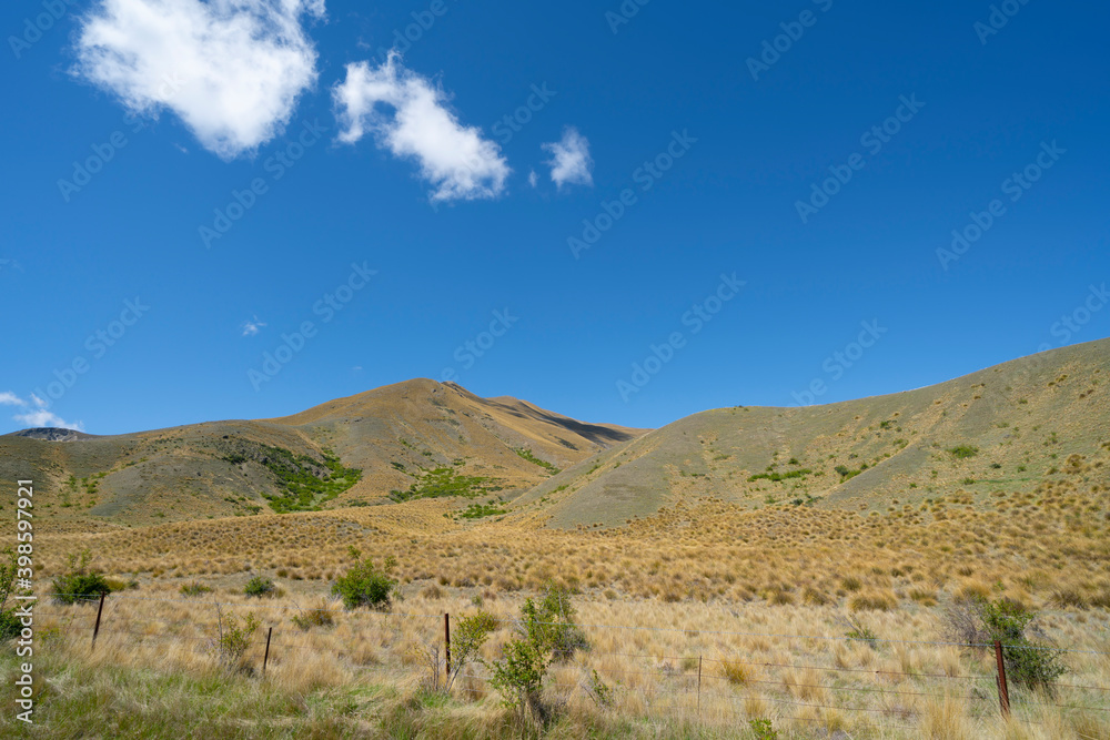 Peaks and tussock covered valleys of Lindis Pass, famous road trip.
