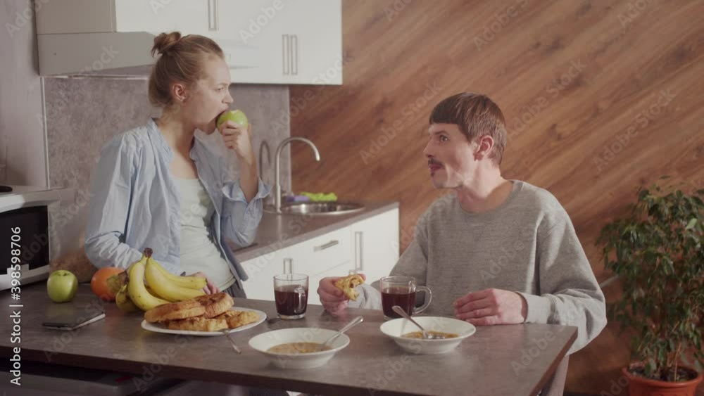 A happy family has lunch in the sunlit kitchen of their new home. A plate of soup, pies, fruit on the table. Communication between husband and wife. A happy family has lunch in the sunlit kitchen of their new home. A plate of soup, pies, fruit on the table. Communication between husband and wife.