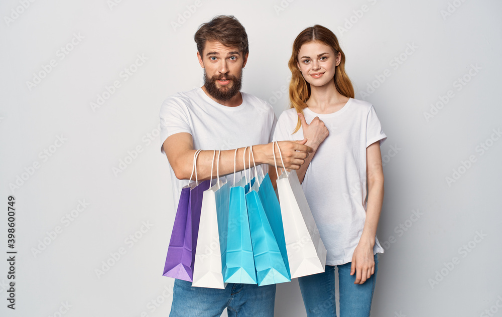 Happy young couple in white T-shirts with packages in hands Shopping is joy Happy young couple in white T-shirts with packages in hands Shopping is joy