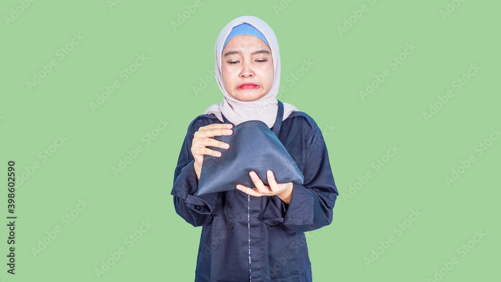 Surprised hijab model being short of money, looks with shocked expression in wallet, has not enough money for paying for her purchase, isolated over color background. People and financial problems Surprised hijab model being short of money, looks with shocked expression in wallet, has not enough money for paying for her purchase, isolated over color background. People and financial problems