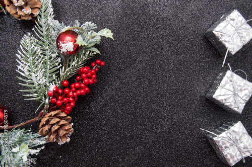 Christmas composition. Wreath made of christmas tree branches and red berries and gift boxes on black background.