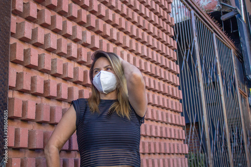 stylish hispanic woman wearing n95 face mask on the street