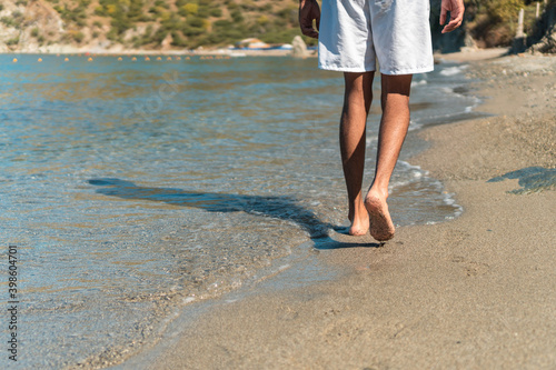 man's bare feet walking at a beach