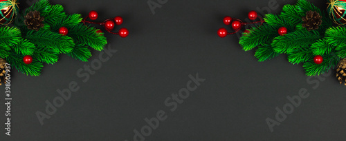 Christmas background, symmetrical composition with fir branches and red berries on black, copy space, banner, top view