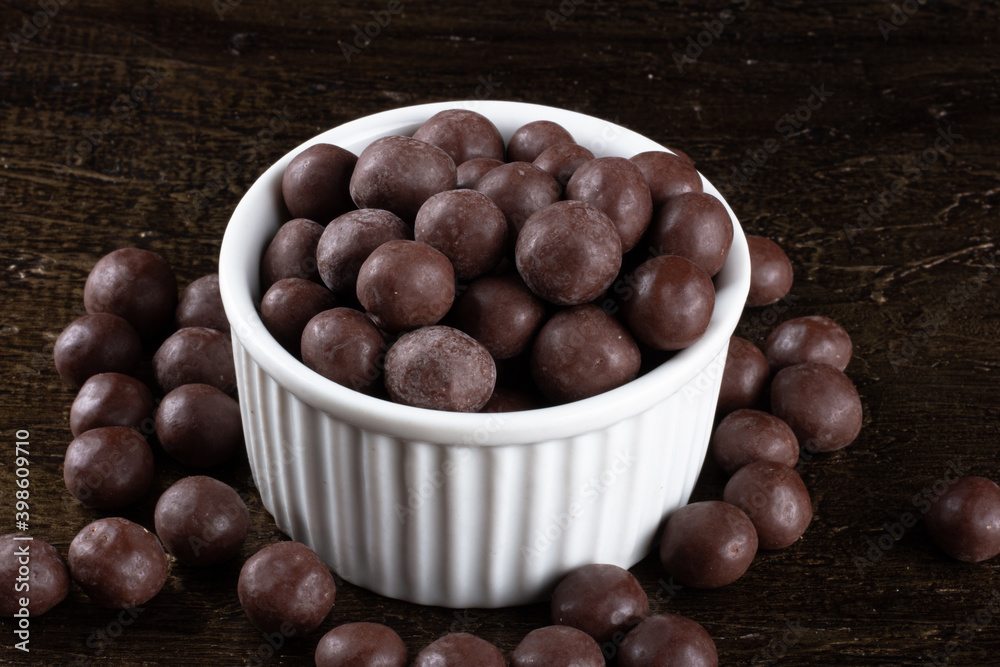 Obraz premium Chocolate balls in white bowl on rustic background.