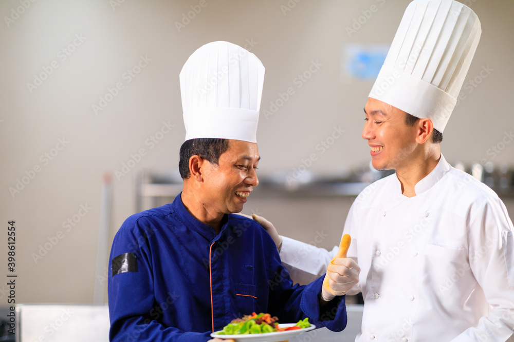 The male exclusive chef doing food testing with his helper in the kitchen The male exclusive chef doing food testing with his helper in the kitchen