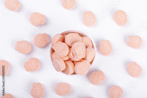 Top view of animal drawings on pink ecstasy pills in a lid isolated on white background
