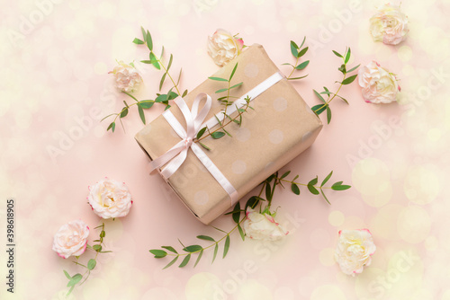Gift box and beautiful flowers on color background