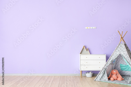 Fotografia Chest of drawers and childish wigwam near color wall