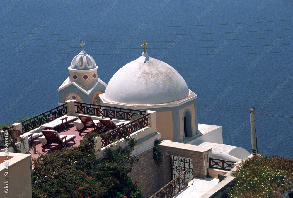 View of Santorini white domed church and Church bells with  house roof in Santorini, Greece. 