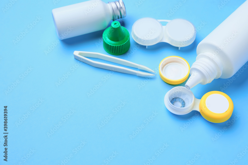 Containers with contact lenses, solutions and tweezers on color background Containers with contact lenses, solutions and tweezers on color background