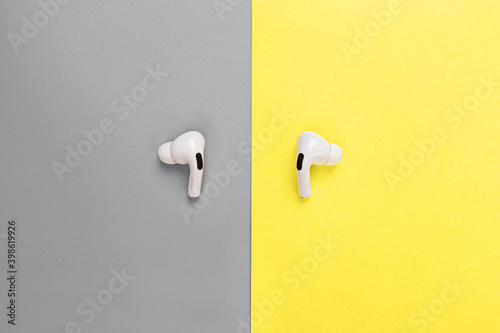 Desktop flat lay with wireless headphones. Colors of the year 2021: ultimate gray and illuminating. Trendy colors concept, mockup with copy space
