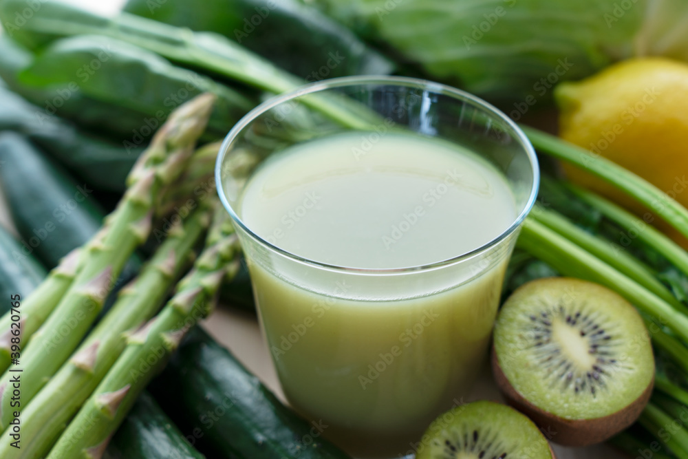 A lot of green vegetables placed on a wooden background and a glass of vegetable juice A lot of green vegetables placed on a wooden background and a glass of vegetable juice