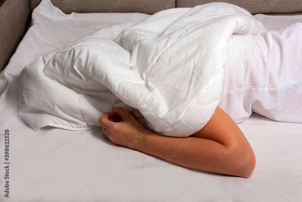 Woman's hands are visible from under the covers as a symbol of fight against insomnia. Tired and exhausted person has nightmares. Woman's hands are visible from under the covers as a symbol of fight against insomnia. Tired and exhausted person has nightmares.
