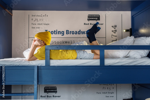 Boy in yellow tshirt and hat on blue two-tier bunk bed photo