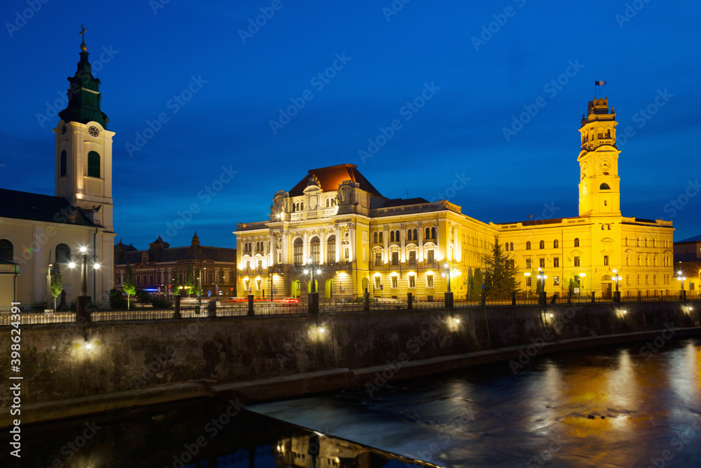 Illuminated City Hall on Oradea embankment in twilight, Romania