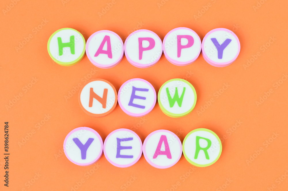 Top view of alphabet erasers with text HAPPY NEW YEAR over orange background. Top view of alphabet erasers with text HAPPY NEW YEAR over orange background.