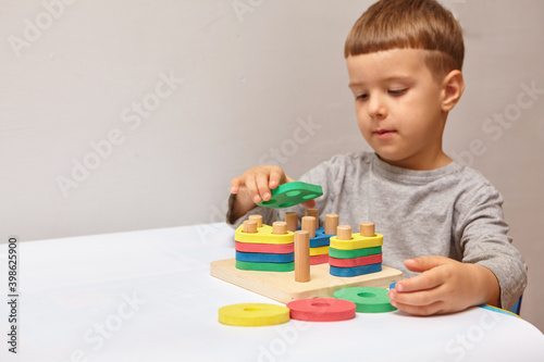 The boy is playing in his room. Learning shapes and colors. A child plays with a sorter. Educational logic toys for kid's. Montessori Games for Child Development.