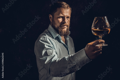 Solid bearded man in shirt with glass of whisky