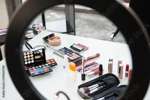 Beauty blogger concept of ring light for makeup with Female decorative cosmetic with lipstick and eyeshadow palette on the table