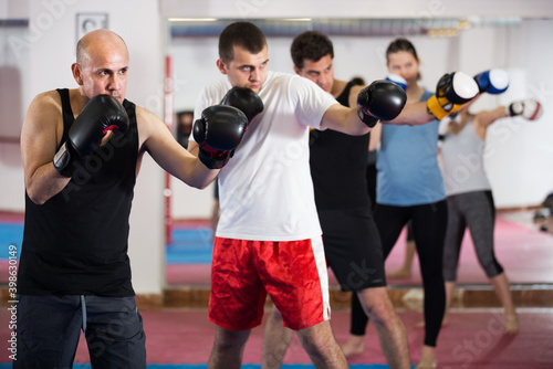 Positive sports people of different ages training in the boxing hall.