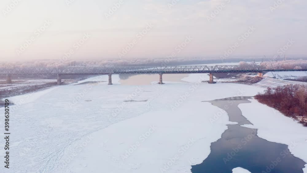 Aerial view overlooking the frozen River during the winter. Bridge over the river in the background. Clear winter morning sky. High quality. Aerial view overlooking the frozen River during the winter. Bridge over the river in the background. Clear winter morning sky. High quality.