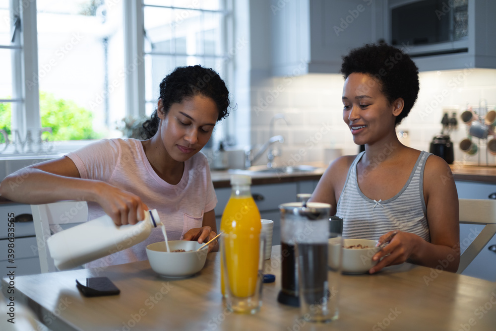 Mixed race same sex female couple having breakfast in kitchen Mixed race same sex female couple having breakfast in kitchen