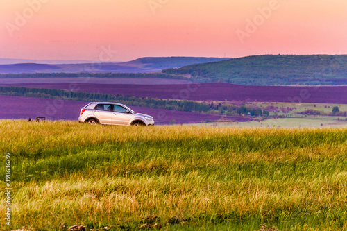 Russia Samara April 2020: The car moves along the road along the field through a colorful steppe valley in the early foggy morning. photo