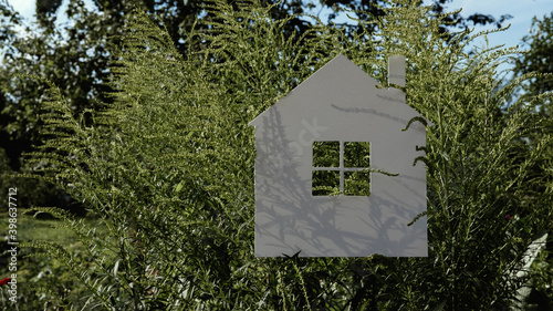 White paper house on a background of green leaves