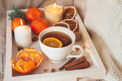 A wooden tray with tea, tangerines, nuts and spices on a beige plaid. Winter breakfast. The concept of hygge.