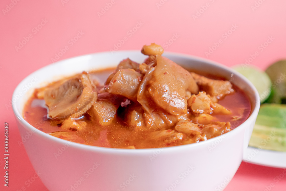 Exquisite Mexican Menudo on a white plate accompanied by a dish with condiments on the back. Exquisite Mexican Menudo on a white plate accompanied by a dish with condiments on the back.